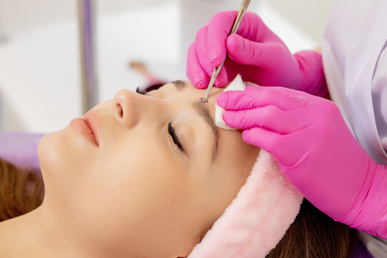 Cosmetologist at spa beauty salon doing acne treatment using